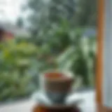 A serene view of rain falling against a window with a steaming cup of tea in the foreground
